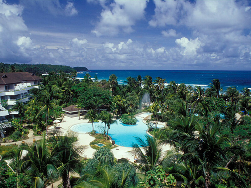 Das Resort liegt am Karon Beach, einem der schönsten der langgezogenen Naturstrände von Phuket. Hier kann man wunderschöne Sonnenuntergänge beobachten. Nach Phuket-Stadt sind es rund 20 km, Patong Beach mit den beliebtesten Nachtclubs der Insel liegt nur eine kurze Fahrt entfernt. Das Resort befindet sich auf einem rund 8 ha großen Anwesen, das auf einer Länge von ca. 500 m direkt an den Strand angrenzt. Die 5 Swimmingpools, der üppige Garten und die niedrigen Gebäude sind die Markenzeichen des Resorts. Zum internationalen Flughafen Phuket sind es rund 48 km (über die Straßen). Thavorn Palm Beach Resort